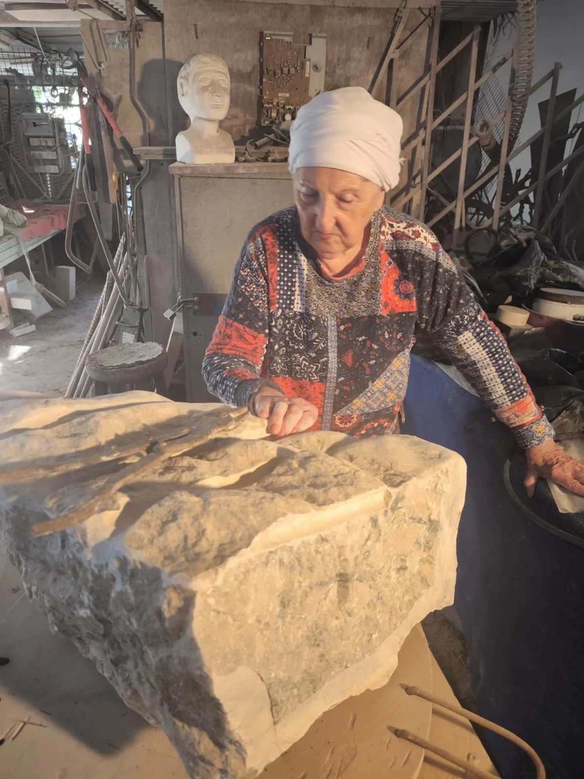 מטי יולזרי לצד גוש אבן גולמי בסטודיו בקיבוץ חולדה